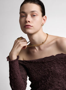 Handcrafted necklace with bronze links plated in 24K gold and raw emerald details. Its organic and sculptural design makes it a unique statement piece, perfect for those seeking sophisticated and timeless jewelry.